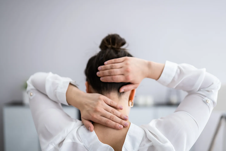 A woman holding her back and back of her head.