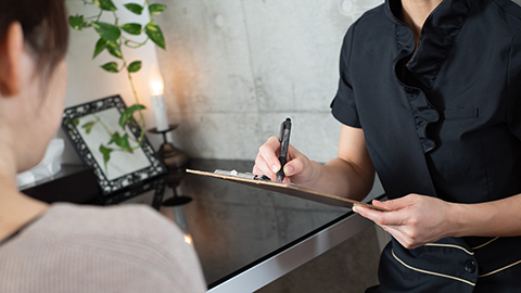 A massage therapist in a black uniform who fills in a medical record at a spa.