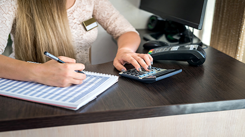 Image of a person using their calculator at their desk.