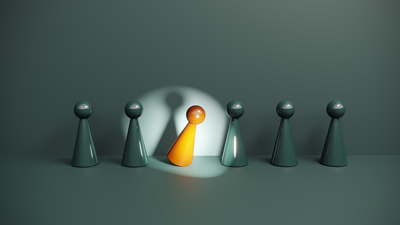 A single orange figure steps forward under a focused spotlight while identical figures remain in the background.