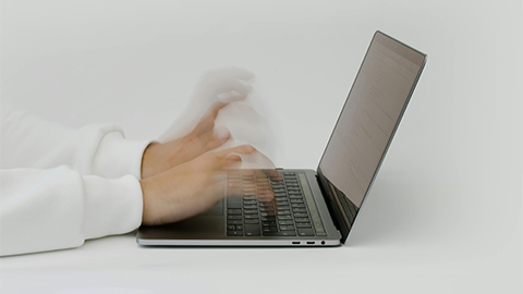 A person typing quickly on a laptop keyboard.