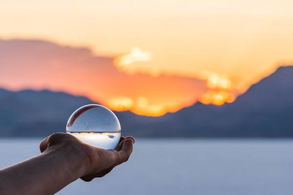 colorful landscape background with hand holding crystal ball near Salt Lake City, Utah and mountain view and sunset