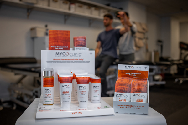 Myco Clinic products are displayed while one man helps another stretch in the background.