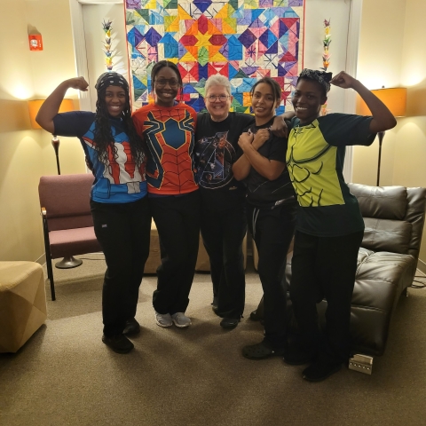 Five people post in superhero T-shirts.