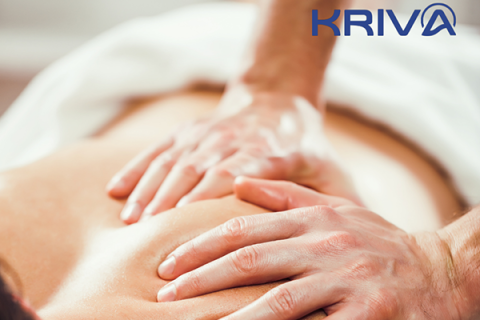 A massage therapist's hands apply pressure to a client's upper back.