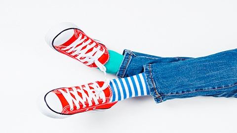 Image of a person crossing their legs wearing red shoes.