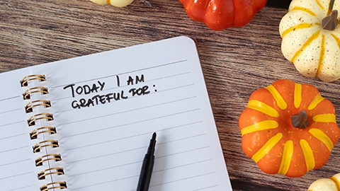 handwritten text in notebook with pumpkins on wooden background.